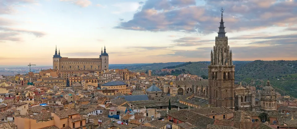 Toledo skyline at sunset with the Alcázar and cathedral tower lit in golden tones